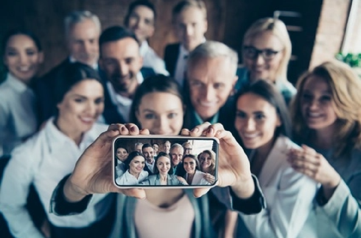 Nazdjęciu grupa ludzi robiąca sobie zdjęcie smartfonem.