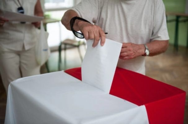 Na zdjęciu mężczyzna wrzucający kartę do głosowania do urny wyborczej